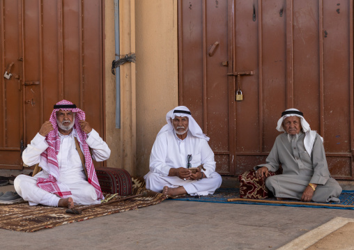 Old sausi men in traditional clothing sit on carpet, Najran Province, Najran, Saudi Arabia