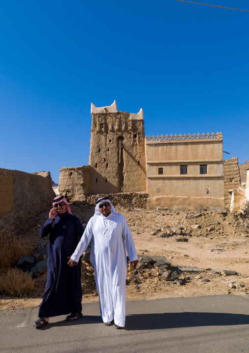 Saudi men passing in front of traditional clay and silt homes in a village, Asir Province, Ahad Rafidah, Saudi Arabia