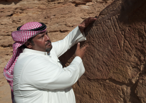 Saudi man showing rock inscriptions in Qadeer sand stone castle, Al-Jawf Province, Sakaka, Saudi Arabia