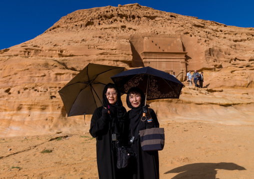 Japanese tourists in front of a nabataean tomb in madain saleh archaeologic site, Al Madinah Province, Al-Ula, Saudi Arabia
