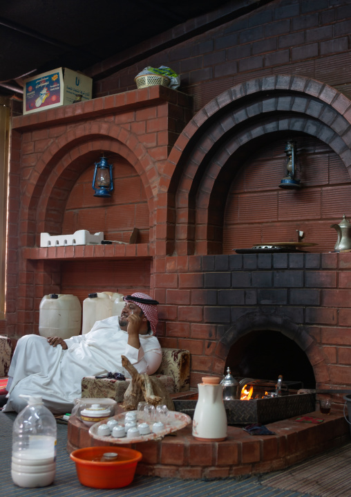 Saudi man resting in a chalet near a fireplace, Najran Province, Najran, Saudi Arabia