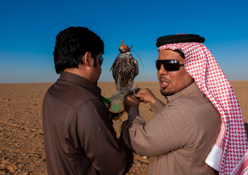 Saudi men with falcon perching on hand, Al-Jawf Province, Sakaka, Saudi Arabia