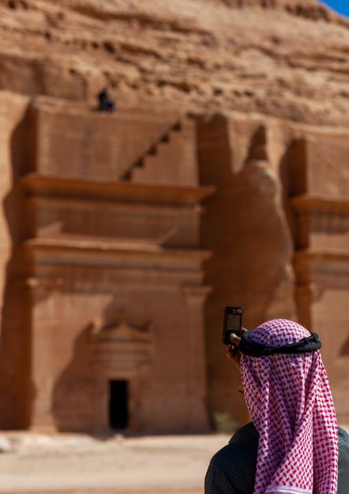 Saudi tourist in front of a nabataean tomb in madain saleh archaeologic site, Al Madinah Province, Al-Ula, Saudi Arabia