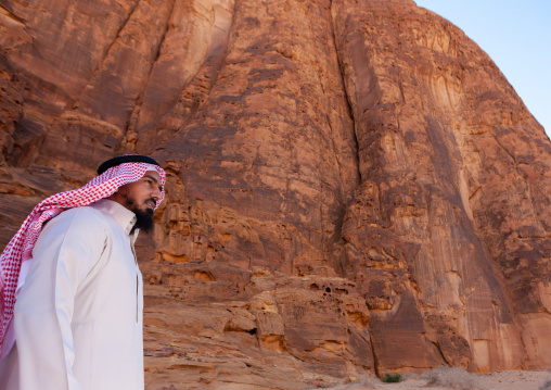 Saudi man in front of a hill in madain saleh archaeologic site, Al Madinah Province, Al-Ula, Saudi Arabia