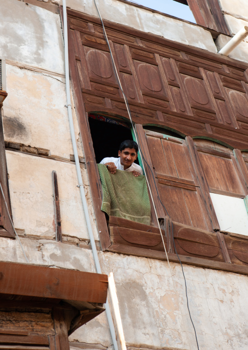Man looking out from a house with wooden mashrabia and rowshan in the old quarter, Hijaz Tihamah region, Jeddah, Saudi Arabia