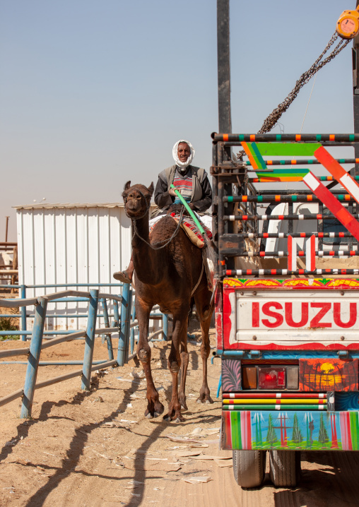 Rashaida sudanese man riding a camel in the market, Riyadh Province, Riyadh, Saudi Arabia
