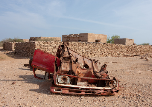 Car wreck in front of old turkish houses, Jizan Region, Farasan island, Saudi Arabia