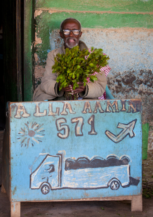 A Senior Khat Seller Standing Outside A House In Front Of A Painted Sign, Baligubadle, Somaliland