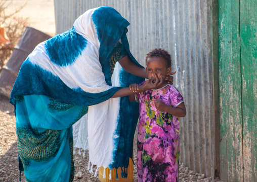 Somali mother washing the face of her daughter outside of their house, Woqooyi Galbeed province, Baligubadle, Somaliland