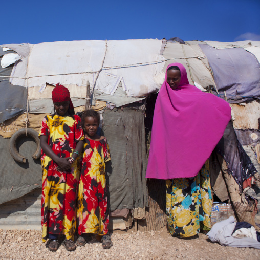 Mother Wearing A Pink Hijab And Two Teenage Girls With The Same Colorful Clothes Outside Their Slum Hut, Baligubadle, Somaliland