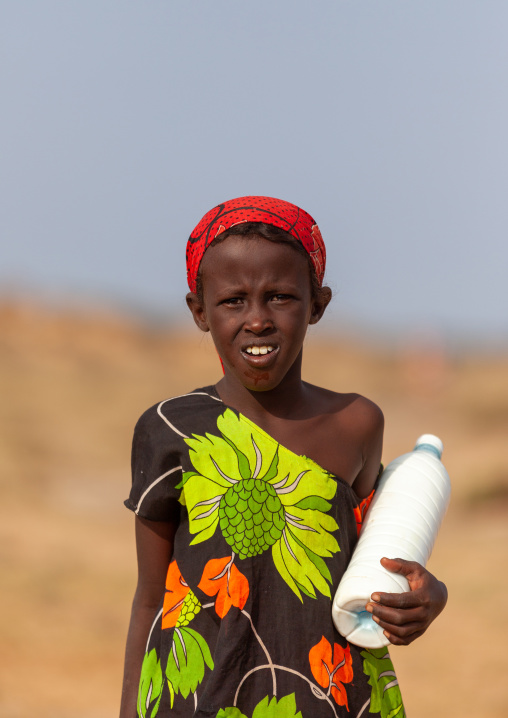 A nomad girl carrying a bottle of camel milk in the desert, Awdal region, Zeila, Somaliland