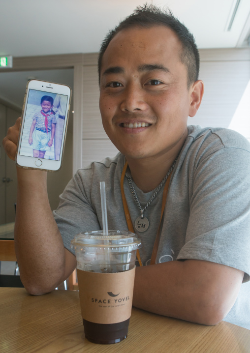 North korean defector joseph park in yovel cafe showing a picture of himself taken in north korea, National capital area, Seoul, South korea