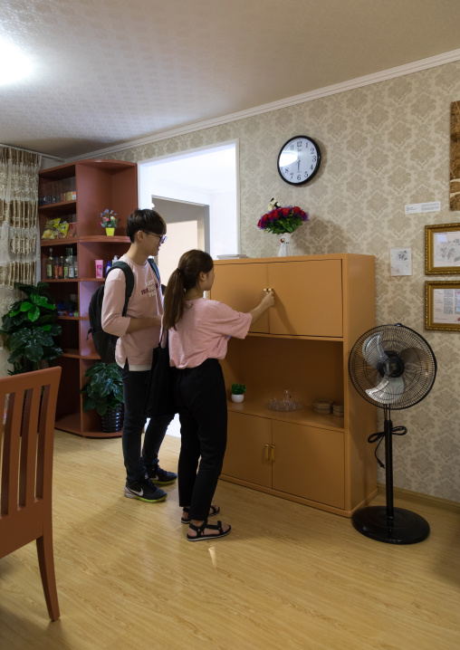 South Korean visitors looking in a cupboard during the exhibition Pyongyang sallim at architecture biennale showing a north Korean apartment replica, National Capital Area, Seoul, South Korea