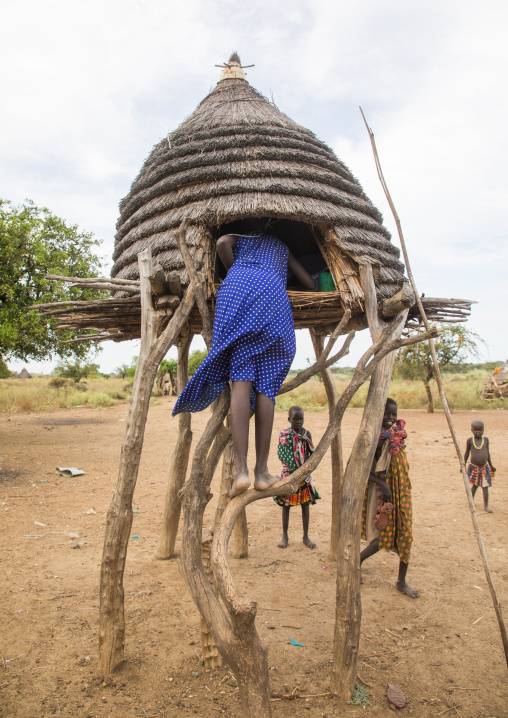 Toposa tribe girl climbing in a granary in a village, Namorunyang State, Kapoeta, South Sudan