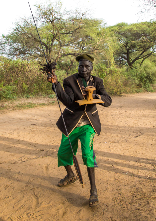 Toposa tribe man dancing with a spear and a wooden seat, Namorunyang State, Kapoeta, South Sudan