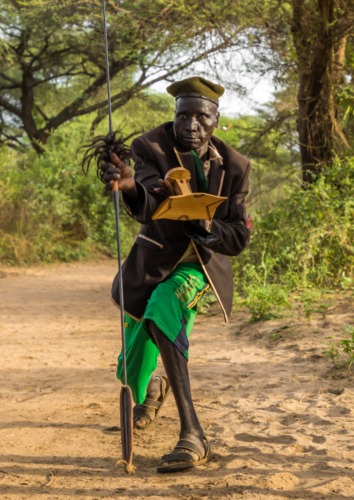 Toposa tribe man dancing with a spear and a wooden seat, Namorunyang State, Kapoeta, South Sudan