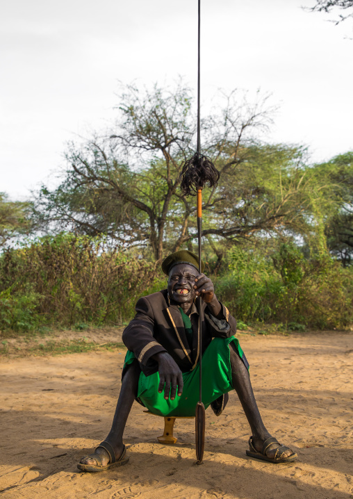 Toposa tribe man sit on a wooden pillow and holding a spear, Namorunyang State, Kapoeta, South Sudan