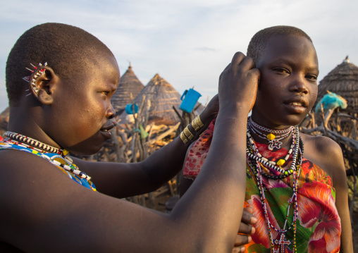 Toposa tribe woman putting earrings to a friend, Namorunyang State, Kapoeta, South Sudan