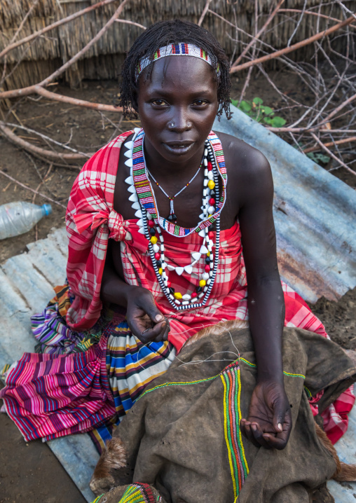 Portrait of a Toposa tribe woman sewing a skirt, Namorunyang State, Kapoeta, South Sudan
