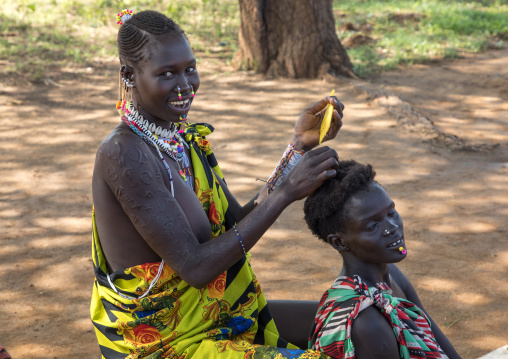 Larim tribe woman making braids to a friend, Boya Mountains, Imatong, South Sudan