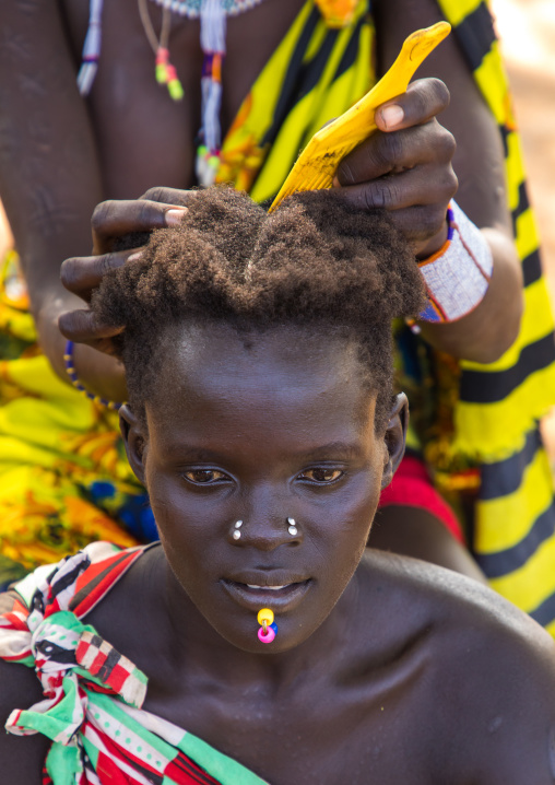 Larim tribe woman making braids to a friend, Boya Mountains, Imatong, South Sudan