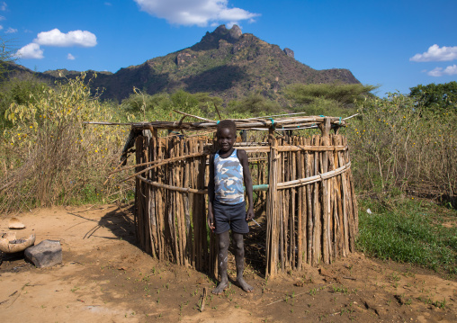 Larim tribe boy in front of a house designed for the children, Boya Mountains, Imatong, South Sudan