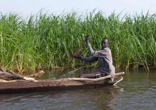 Mundari tribe man rowing in a boat on river Nile, Central Equatoria, Terekeka, South Sudan