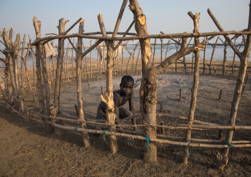 Mundari tribe boy cleaning a fenced area in a cattle camp, Central Equatoria, Terekeka, South Sudan