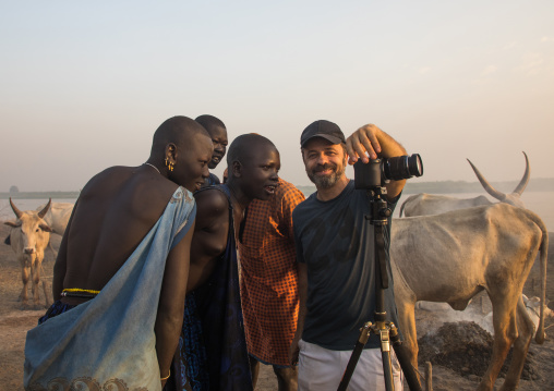 Western tourists showing pictures on his camera to Mundari people, Central Equatoria, Terekeka, South Sudan