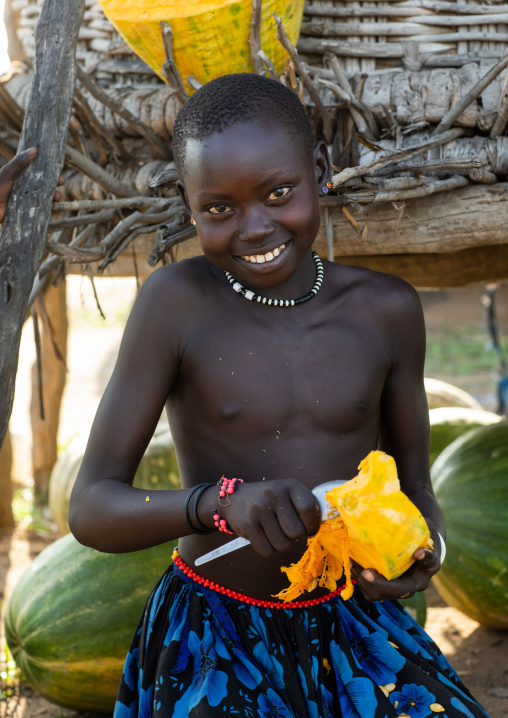 Portrait of a Mundari tribe girl cutting a pumpkin, Central Equatoria, Terekeka, South Sudan