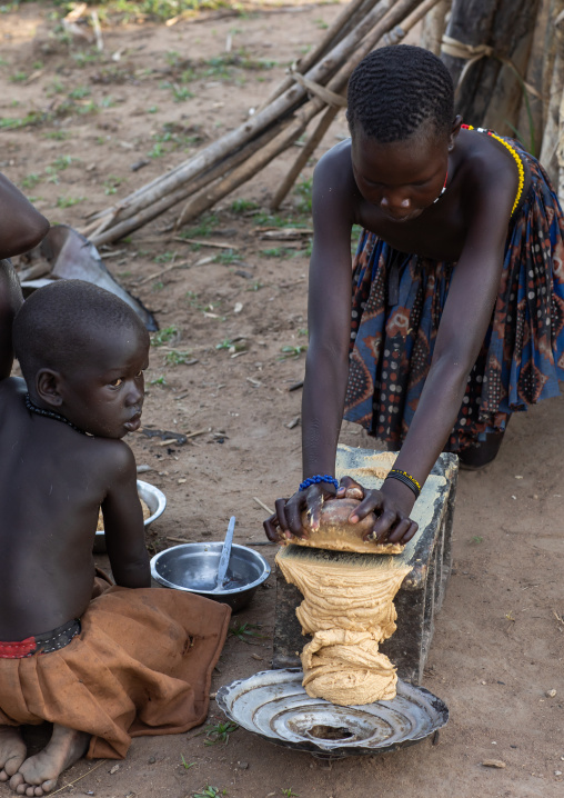 Mundari girl grinding peanuts on a stone, Central Equatoria, Terekeka, South Sudan