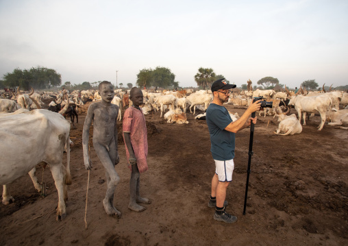 Tourist filming in a Mundari tribe camp with long horns cows, Central Equatoria, Terekeka, South Sudan