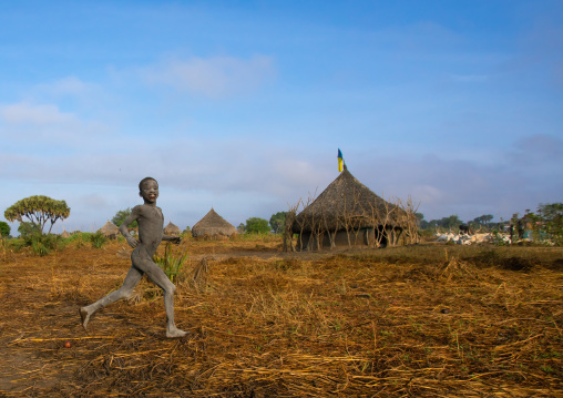 Boy running in front of a traditional Mundari tribe village, Central Equatoria, Terekeka, South Sudan