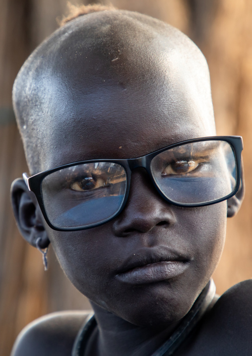 Portrait of a Mundari tribe girl wearing the glasses of a tourist, Central Equatoria, Terekeka, South Sudan