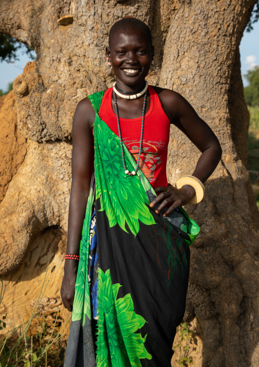 Portrait of a smiling Mundari tribe woman in front of a tree, Central Equatoria, Terekeka, South Sudan