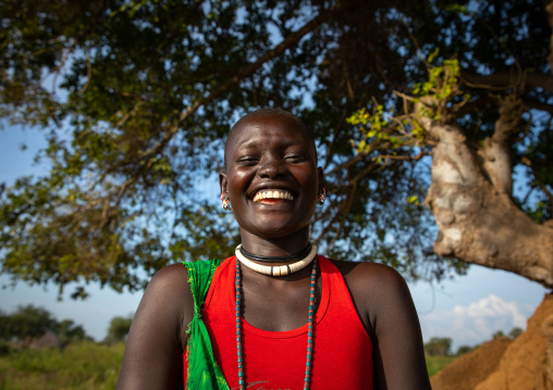 Portrait of a smiling Mundari tribe woman in front of a tree, Central Equatoria, Terekeka, South Sudan