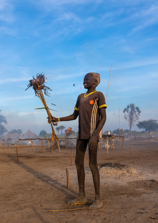 Mundari boy holding a torch to put fire to dried cow dungs, Central Equatoria, Terekeka, South Sudan