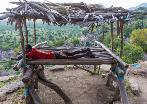 Lotuko tribe man resting on a wood bed, Central Equatoria, Illeu, South Sudan