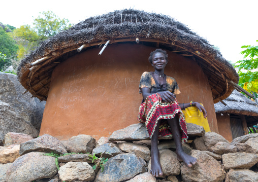 Woman sit in front of a Lotuko tribe thatched house, Central Equatoria, Illeu, South Sudan