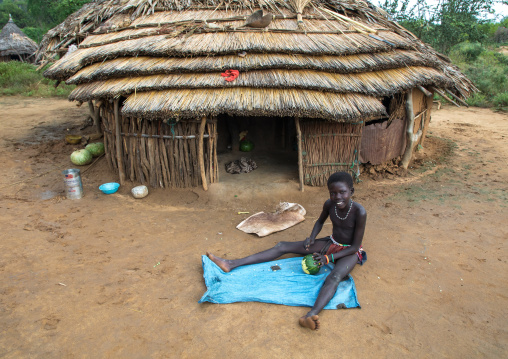 Larim tribe girl cutting a vegetable in front of her house, Boya Mountains, Imatong, South Sudan