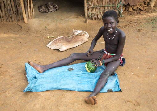 Larim tribe girl cutting a vegetable in front of her house, Boya Mountains, Imatong, South Sudan