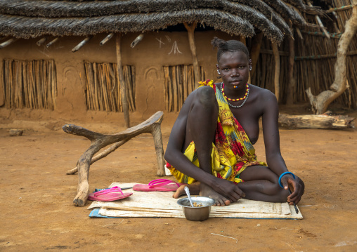 Portrait of a Larim tribe woman eating in front of her house, Boya Mountains, Imatong, South Sudan