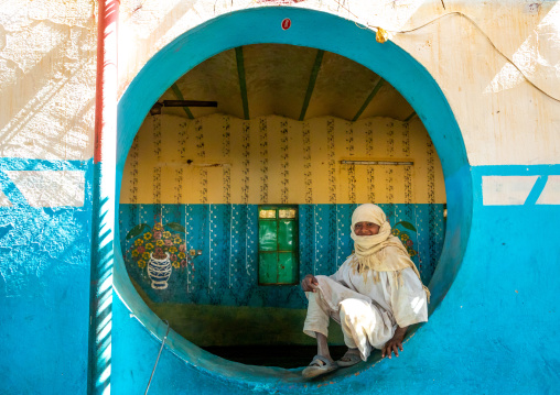 Sudanese boy resting inside a circular window in a restaurant, Khartoum State, Khartoum, Sudan