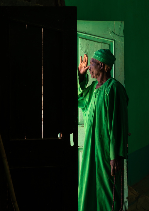 Sufi dervish in green clothes at the entrance of a door, Al Jazirah, Abu Haraz, Sudan