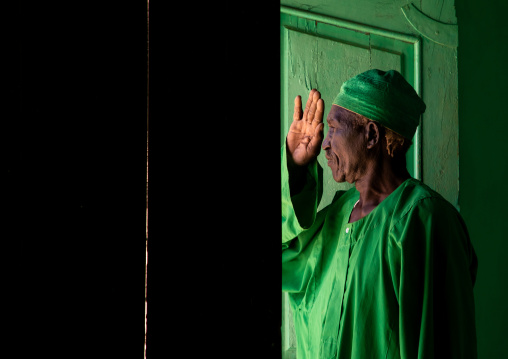 Sufi dervish in green clothes at the entrance of a door, Al Jazirah, Abu Haraz, Sudan