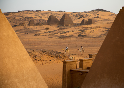Sudanese men and their camels in front of the pyramids of the kushite rulers at Meroe, Northern State, Meroe, Sudan