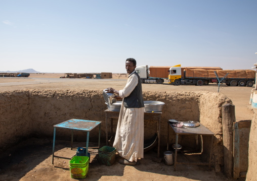 Sudanese man washing plates in an outdoor restaurant on a highway stop, Kassala State, Kassala, Sudan