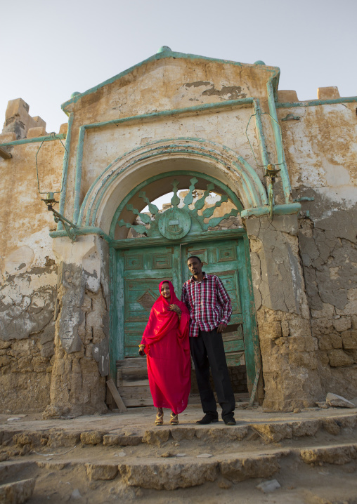 Sudan, Port Sudan, Suakin, couple in front of a huge green door of a ruined ottoman coral buildings