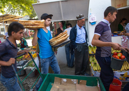 Young men carrying breads and fruits in the alleys of a local market, Gorno-Badakhshan autonomous region, Khorog, Tajikistan