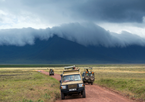 Tanzania, Arusha Region, Ngorongoro Conservation Area, a safari vehicle crosses the savannah plain on the floor of a volcano caldera